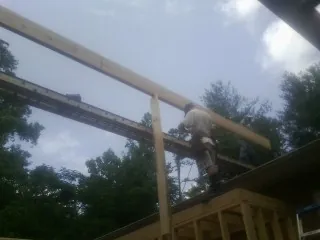 Carpenter setting a ridge beam over a new addition frame — Ice Dam Removal by Roofing Brothers in Kendall Park