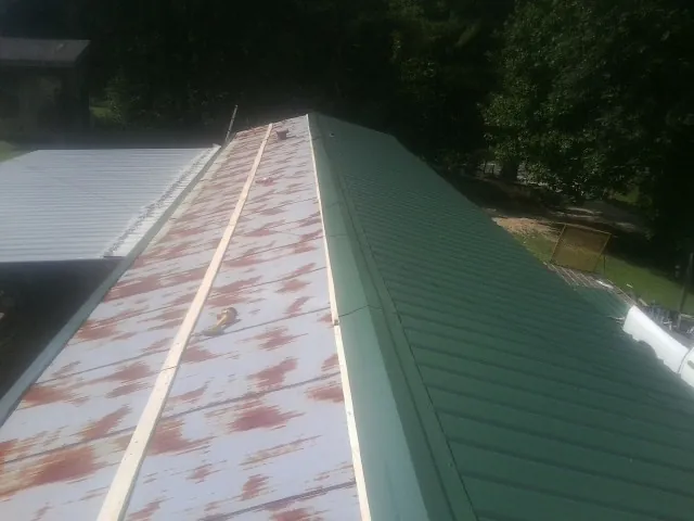 Old rusted panels beside newly installed green metal roofing — Wind Damage Roof Repair by Roofing Brothers in Kendall Park