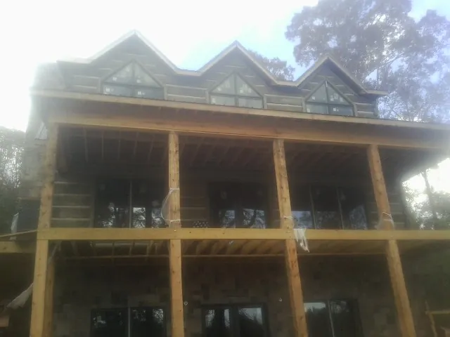 Dormers and porch framing on a large log home under construction — Roof Coating work by our crew in Kendall Park