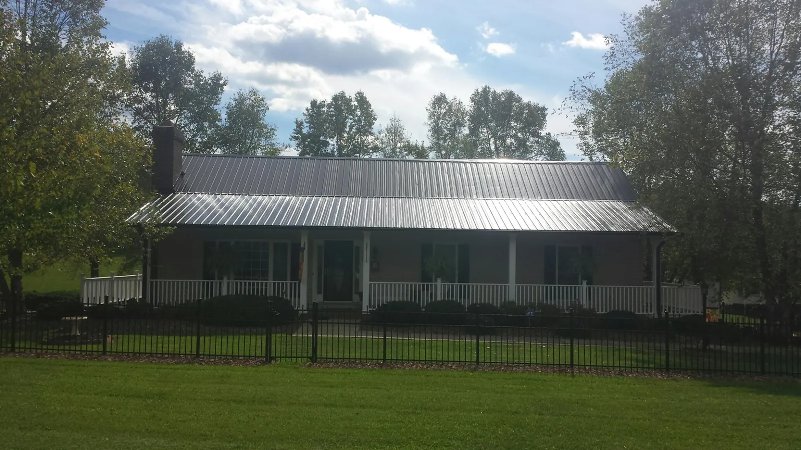 Gray metal roof on a brick ranch with a full width front porch — Gutter Guard Installation work by our crew in Kendall Park