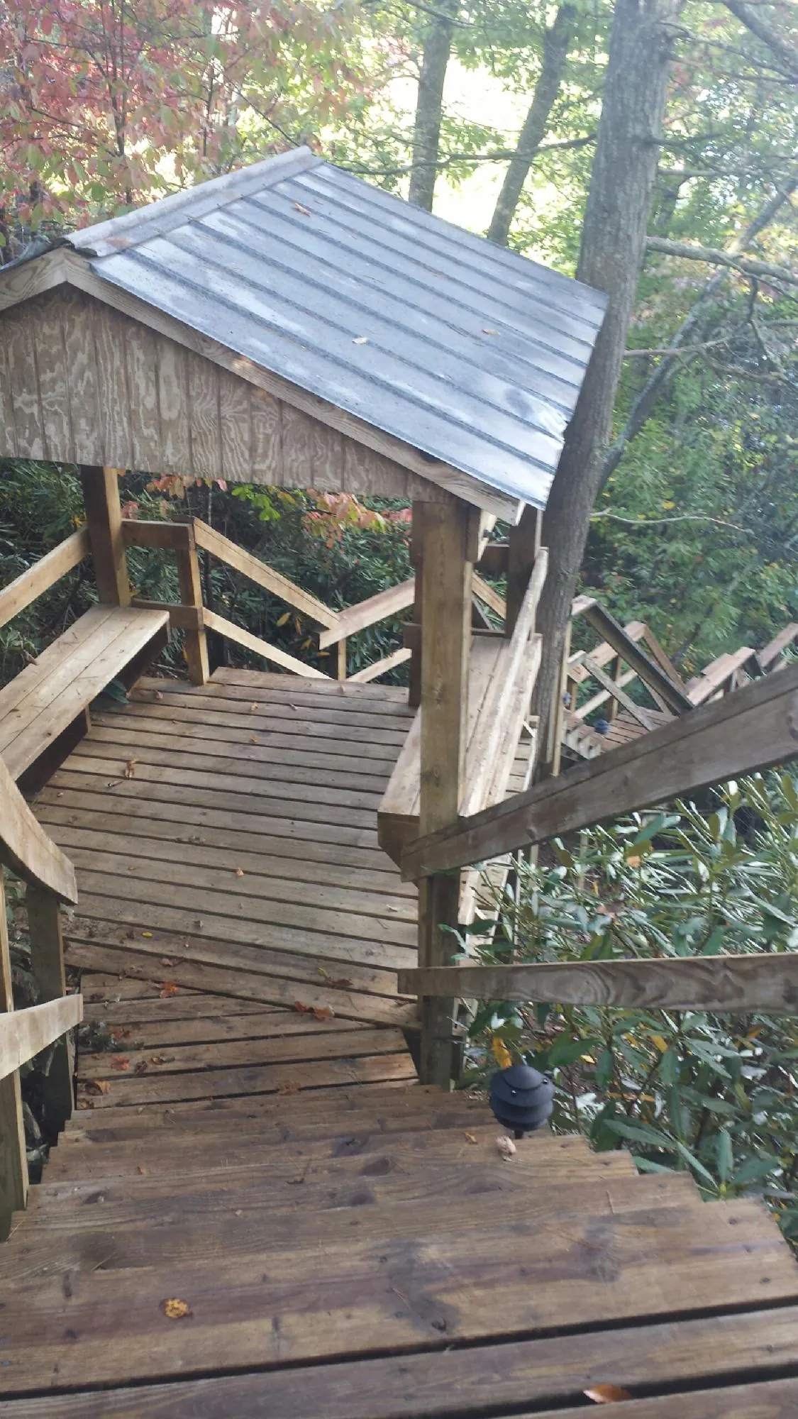 Metal roofed shelter over wooden steps on a wooded walkway — Skylight Repair & Installation work by our crew in Kendall Park