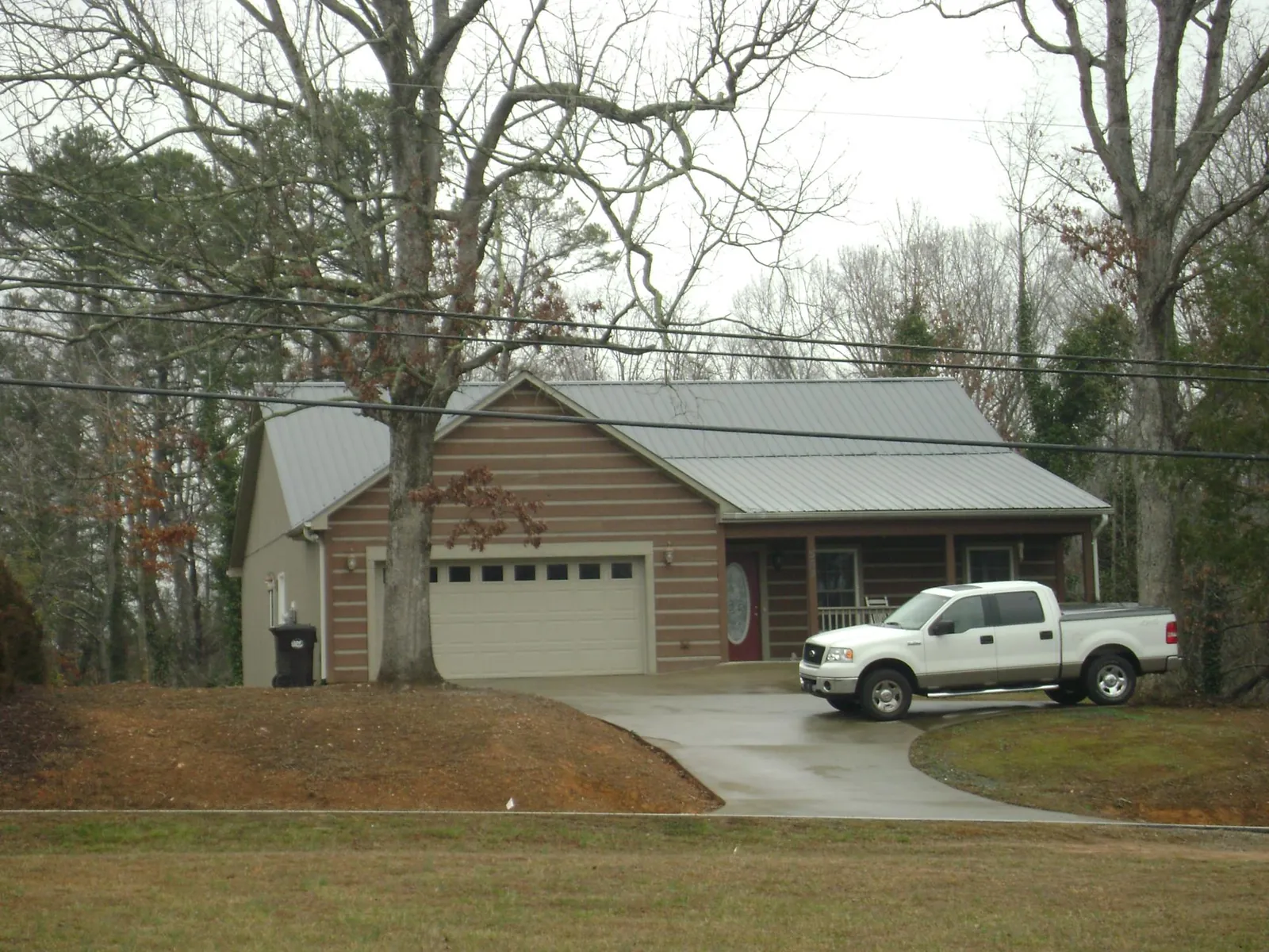 Gray metal roof on a log sided house with an attached two car garage in Kendall Park