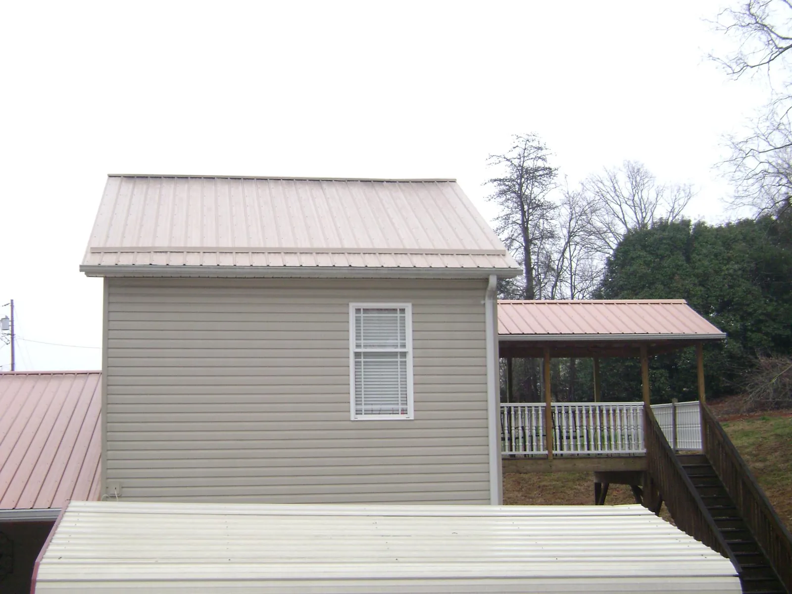 Tan metal roofs on a two story addition and attached porch, from a Roof Replacement job in Kendall Park