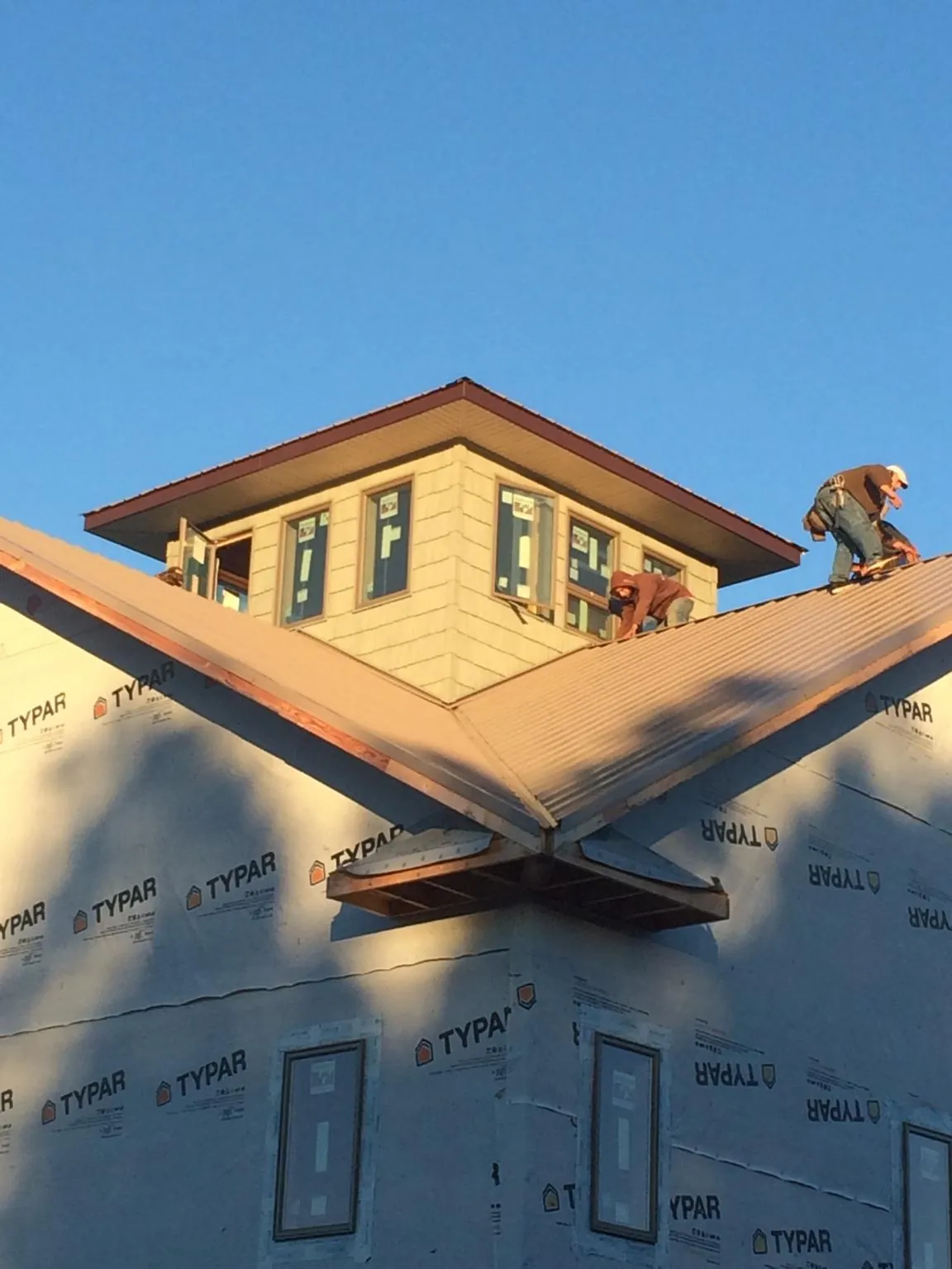 Roofers working around a rooftop cupola on a new metal roof at sunset — Roof Waterproofing in Kendall Park by Roofing Brothers